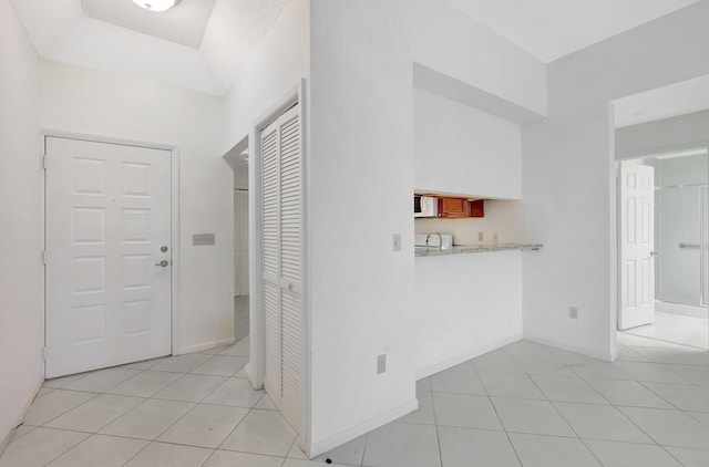 hall featuring a sink, baseboards, and light tile patterned floors