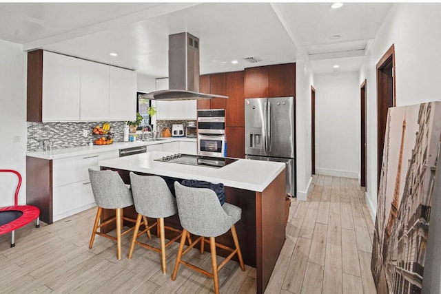 kitchen with stainless steel appliances, modern cabinets, island exhaust hood, and decorative backsplash