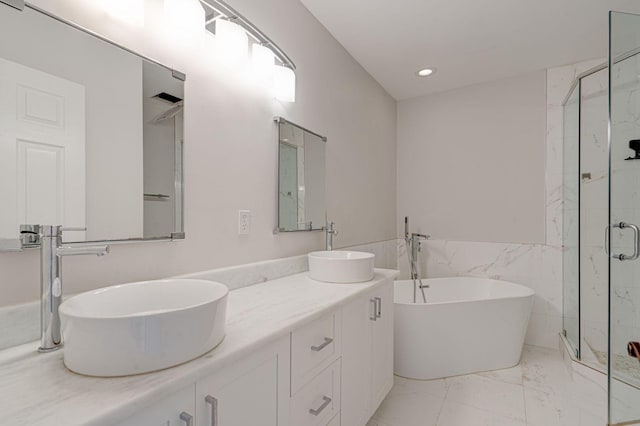 bathroom featuring marble finish floor, a freestanding bath, a sink, and a stall shower