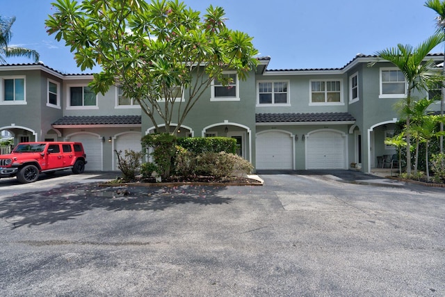 townhome / multi-family property with driveway, an attached garage, and stucco siding