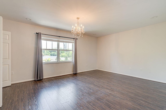 empty room featuring dark wood-style floors, baseboards, and a notable chandelier