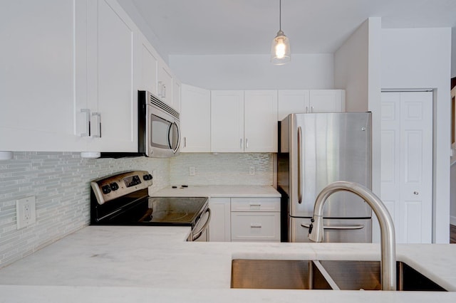 kitchen with light countertops, appliances with stainless steel finishes, white cabinetry, and decorative backsplash