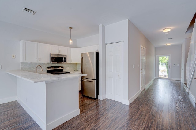 kitchen featuring visible vents, decorative backsplash, a peninsula, stainless steel appliances, and white cabinetry