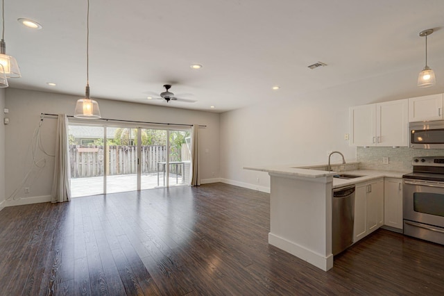 kitchen featuring tasteful backsplash, appliances with stainless steel finishes, open floor plan, white cabinets, and a sink