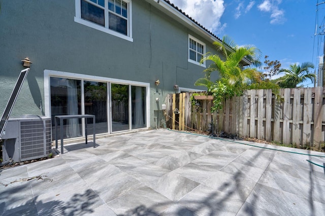 rear view of property featuring a patio area, stucco siding, fence, and central air condition unit