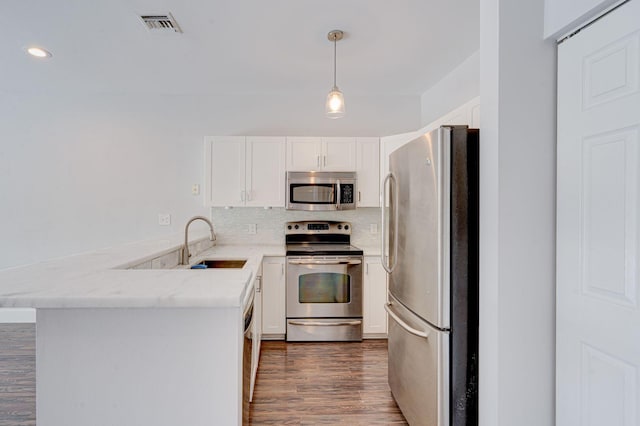 kitchen with tasteful backsplash, visible vents, a peninsula, stainless steel appliances, and a sink