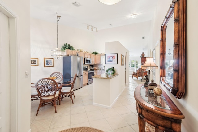 kitchen with light tile patterned floors, a peninsula, visible vents, appliances with stainless steel finishes, and light brown cabinetry