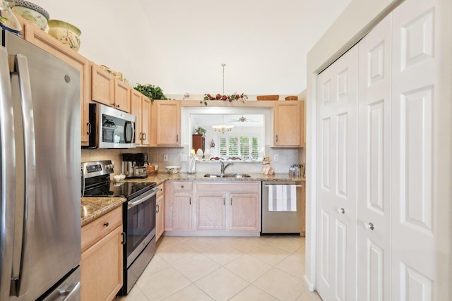 kitchen featuring stainless steel appliances, light brown cabinets, a sink, and decorative backsplash