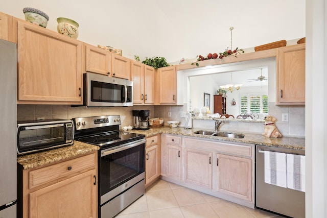 kitchen with a toaster, stainless steel appliances, backsplash, light brown cabinets, and a sink