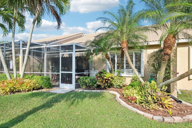 rear view of property with glass enclosure, a yard, a tiled roof, and stucco siding