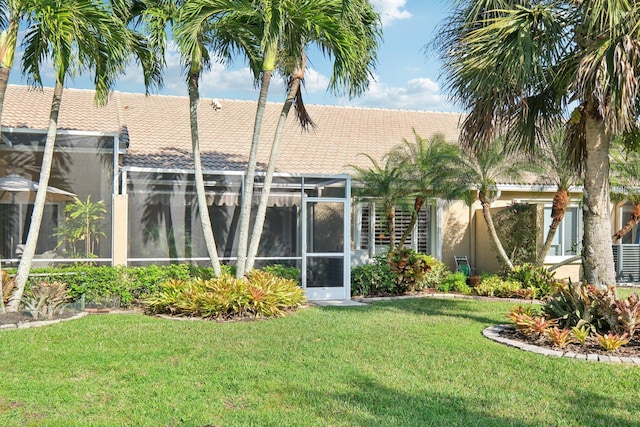 rear view of property with glass enclosure, a lawn, and stucco siding