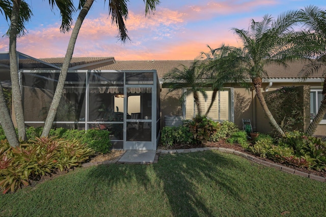 exterior space with glass enclosure, a lawn, and stucco siding