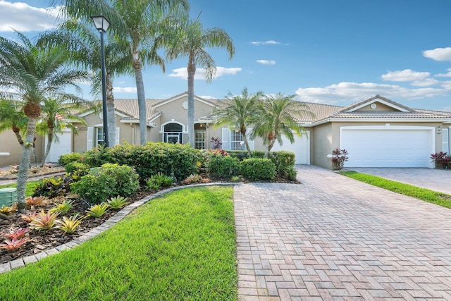 view of front of home with a garage, decorative driveway, a tile roof, and stucco siding