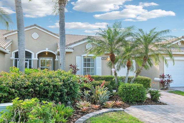 mediterranean / spanish-style home with decorative driveway, a tile roof, and stucco siding