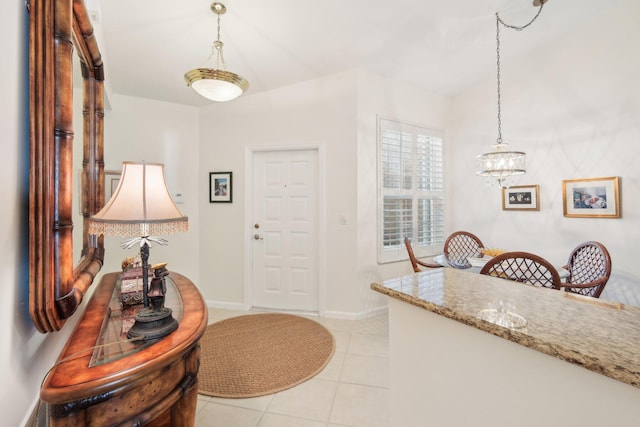 entryway with a notable chandelier, light tile patterned flooring, and baseboards