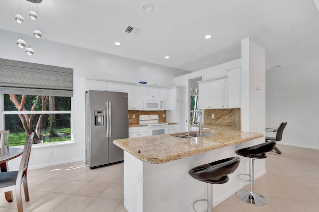 kitchen featuring white appliances, visible vents, a peninsula, a sink, and light tile patterned flooring