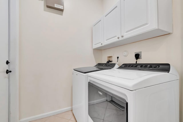 laundry area featuring cabinet space, washing machine and dryer, light tile patterned floors, and baseboards