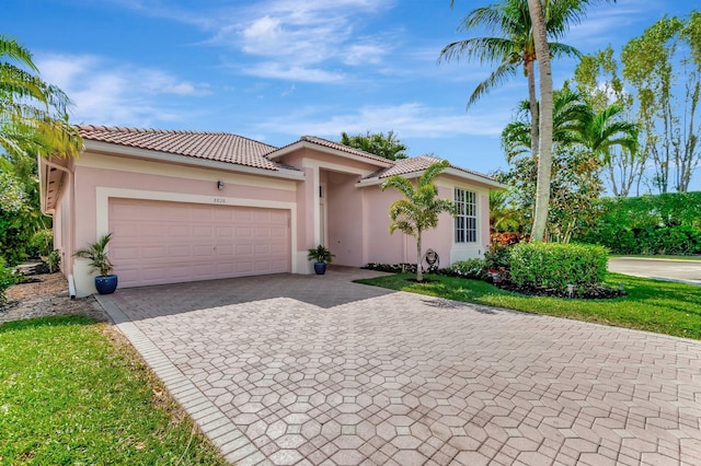 mediterranean / spanish home featuring a tiled roof, decorative driveway, an attached garage, and stucco siding