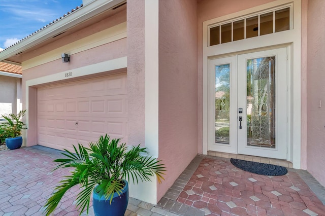 entrance to property with a garage and stucco siding