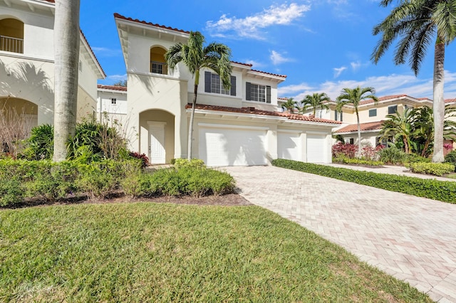 mediterranean / spanish-style house featuring a garage, decorative driveway, a tile roof, and stucco siding