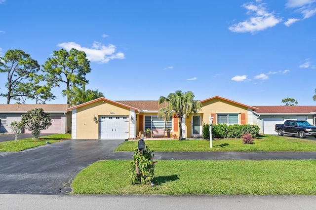 ranch-style home featuring an attached garage, aphalt driveway, a front yard, and stucco siding