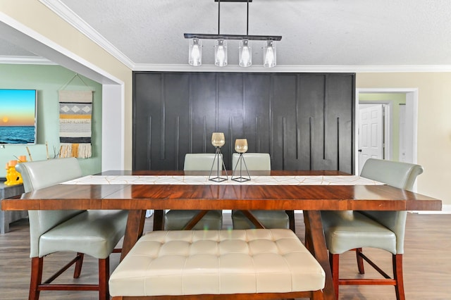 dining room with ornamental molding, a textured ceiling, and wood finished floors