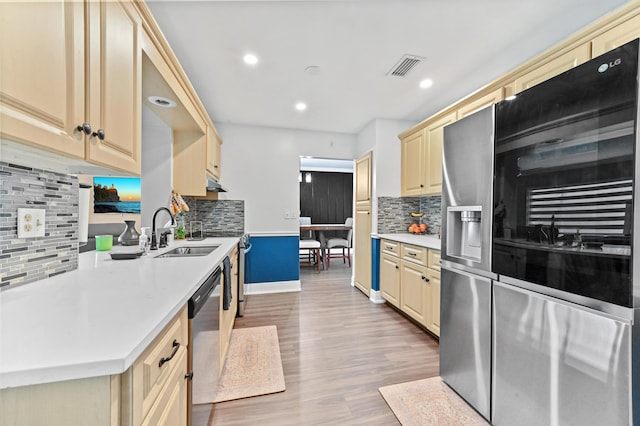 kitchen featuring cream cabinetry, light countertops, appliances with stainless steel finishes, a sink, and wood finished floors