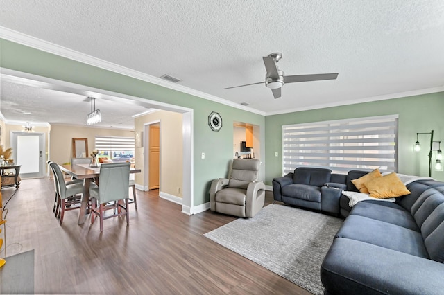 living area featuring ceiling fan, visible vents, crown molding, and wood finished floors