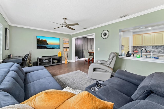 living area featuring ceiling fan, wood finished floors, visible vents, and crown molding