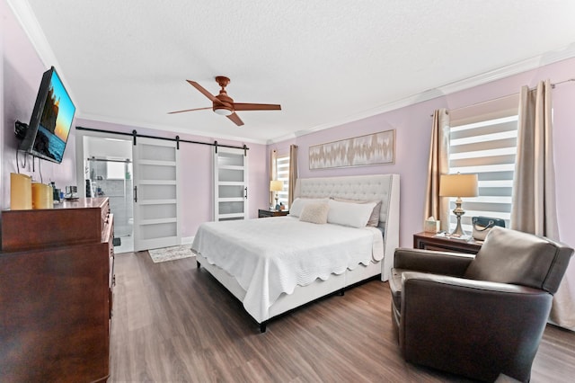 bedroom featuring a barn door, wood finished floors, and crown molding