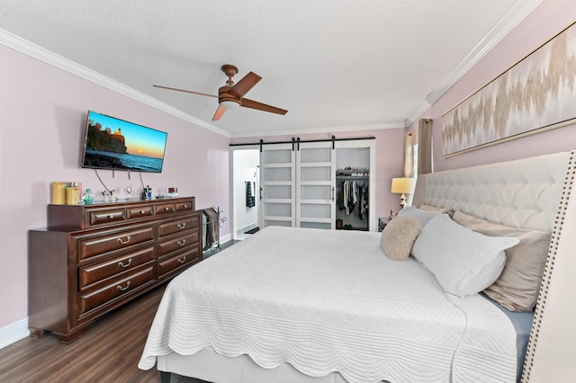 bedroom featuring a barn door, baseboards, dark wood-type flooring, crown molding, and a closet