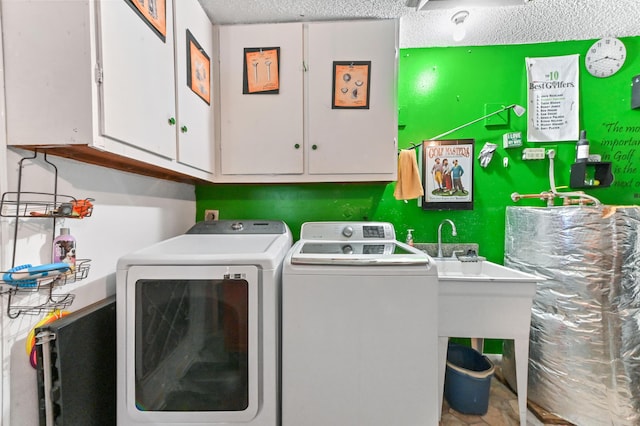 clothes washing area with cabinet space, washing machine and dryer, and a textured ceiling