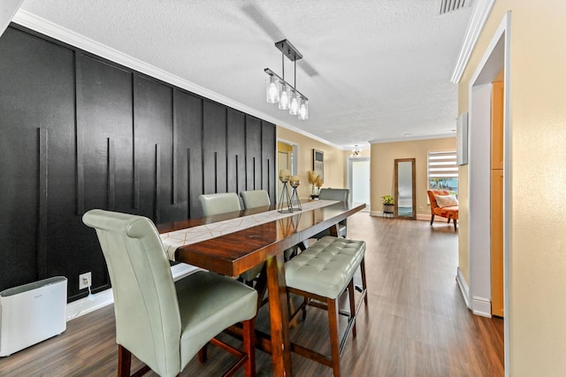 dining room featuring visible vents, crown molding, a textured ceiling, and wood finished floors