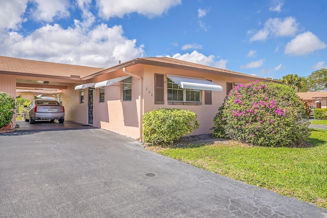 view of front of house featuring aphalt driveway, an attached carport, and stucco siding