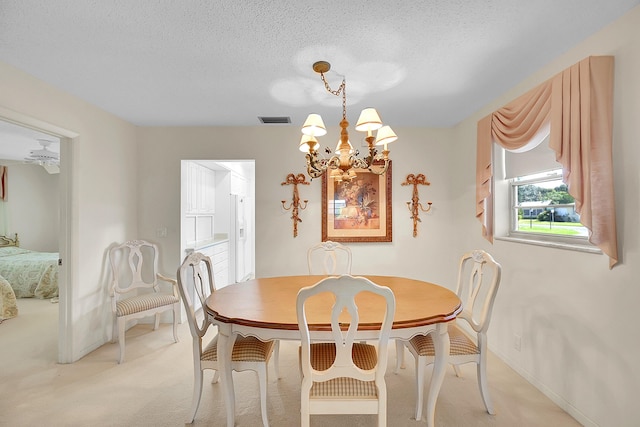 dining space with visible vents, baseboards, light carpet, an inviting chandelier, and a textured ceiling