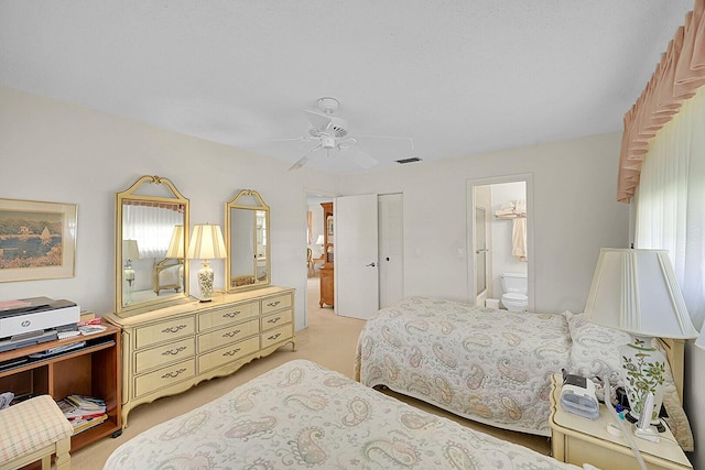 bedroom with a ceiling fan, light colored carpet, a closet, and connected bathroom