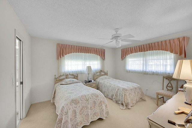 carpeted bedroom featuring baseboards, multiple windows, a textured ceiling, and a ceiling fan