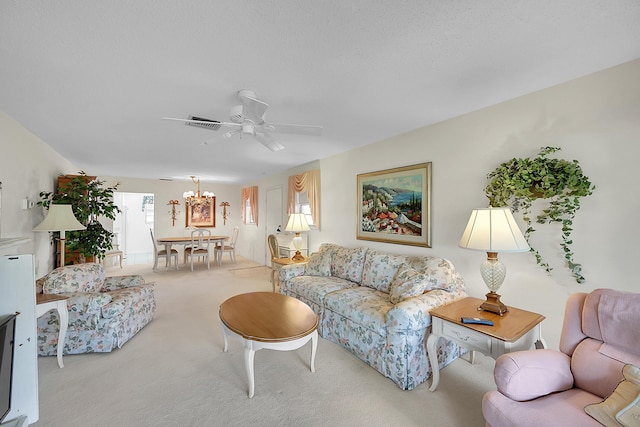 carpeted living room featuring ceiling fan with notable chandelier