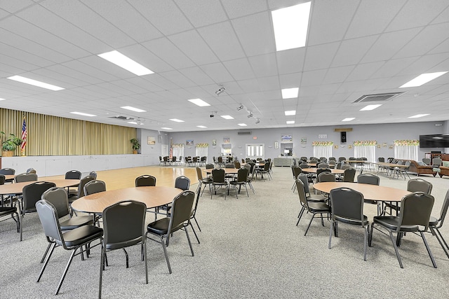 dining room featuring a drop ceiling, visible vents, and light colored carpet