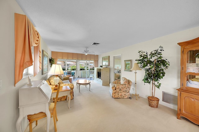 sitting room featuring visible vents, light colored carpet, and a ceiling fan