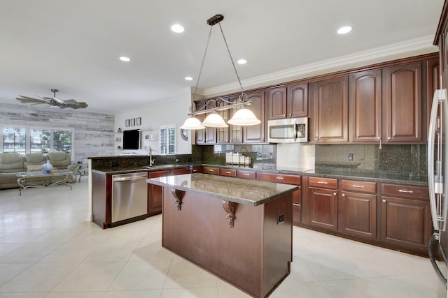 kitchen with a peninsula, a kitchen island, a healthy amount of sunlight, open floor plan, and appliances with stainless steel finishes