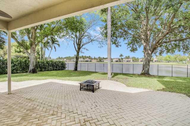 view of patio with a fire pit, a water view, and a fenced backyard