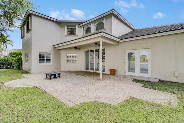 rear view of property featuring a patio, a ceiling fan, french doors, a lawn, and stucco siding