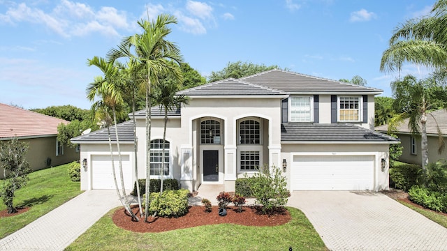 view of front of house with a tile roof, a front lawn, decorative driveway, and stucco siding