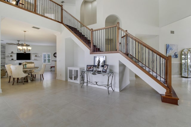 stairway with baseboards, a towering ceiling, visible vents, and an inviting chandelier