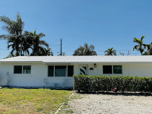 ranch-style house with stucco siding, metal roof, and a front yard