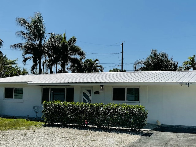 ranch-style house with a standing seam roof, metal roof, and stucco siding