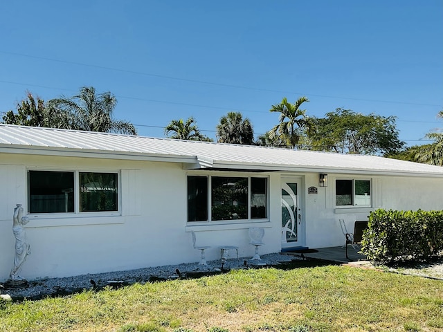 single story home with stucco siding, a front lawn, and metal roof