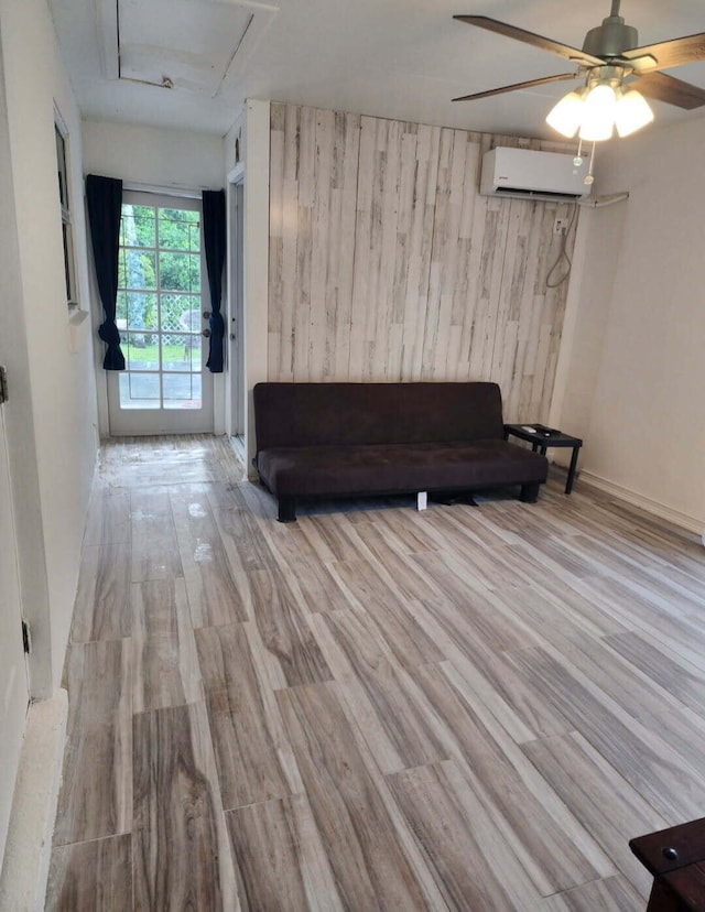 unfurnished living room with an AC wall unit, ceiling fan, and wood finished floors