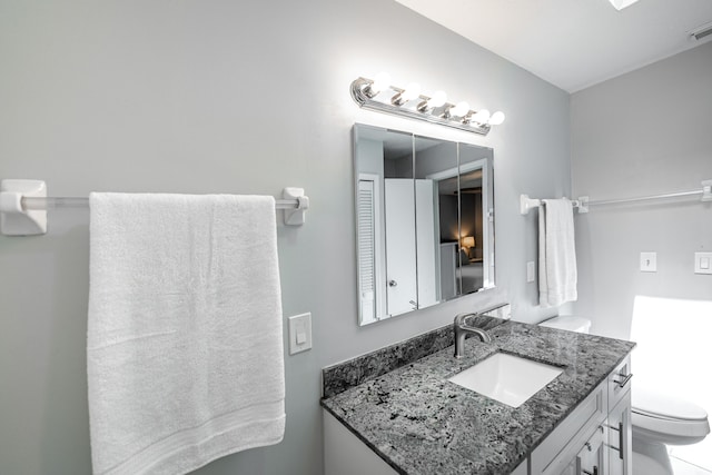 bathroom featuring visible vents, toilet, and vanity